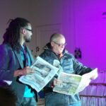 Performers reading a newspaper as part of the performance 'Wendy In Saneland